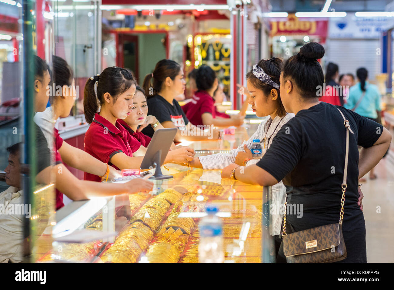 Vientiane, Laos - 9 août 2018 : Jeune femme tente sur un bracelet d'or en présence de son ami et trois femmes vendeurs à Talat Sao Mall. Banque D'Images