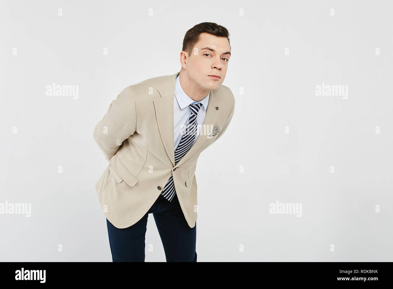 Élégant et beau jeune homme brun dans la chemise blanche avec cravate rayée  beige, dans une veste sportive et en jeans foncé posant à fond blanc, isolé  Photo Stock - Alamy