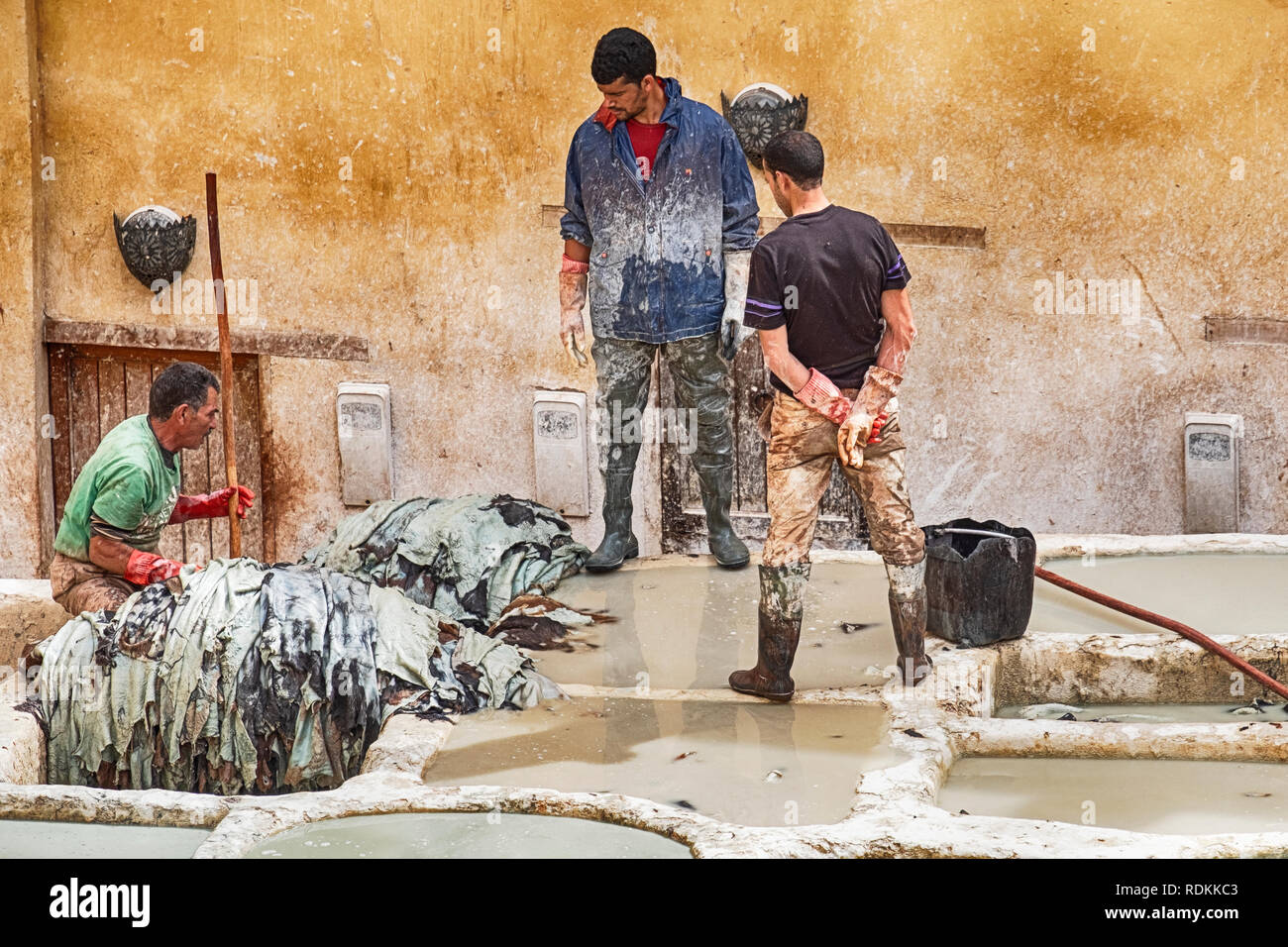 FES, MAROC - 19 octobre 2018 : Trois travailleurs dans la tannerie Chouara à Fes, Maroc faites tremper les peaux dans les fosses de bronzage pour ramollir le leat Banque D'Images