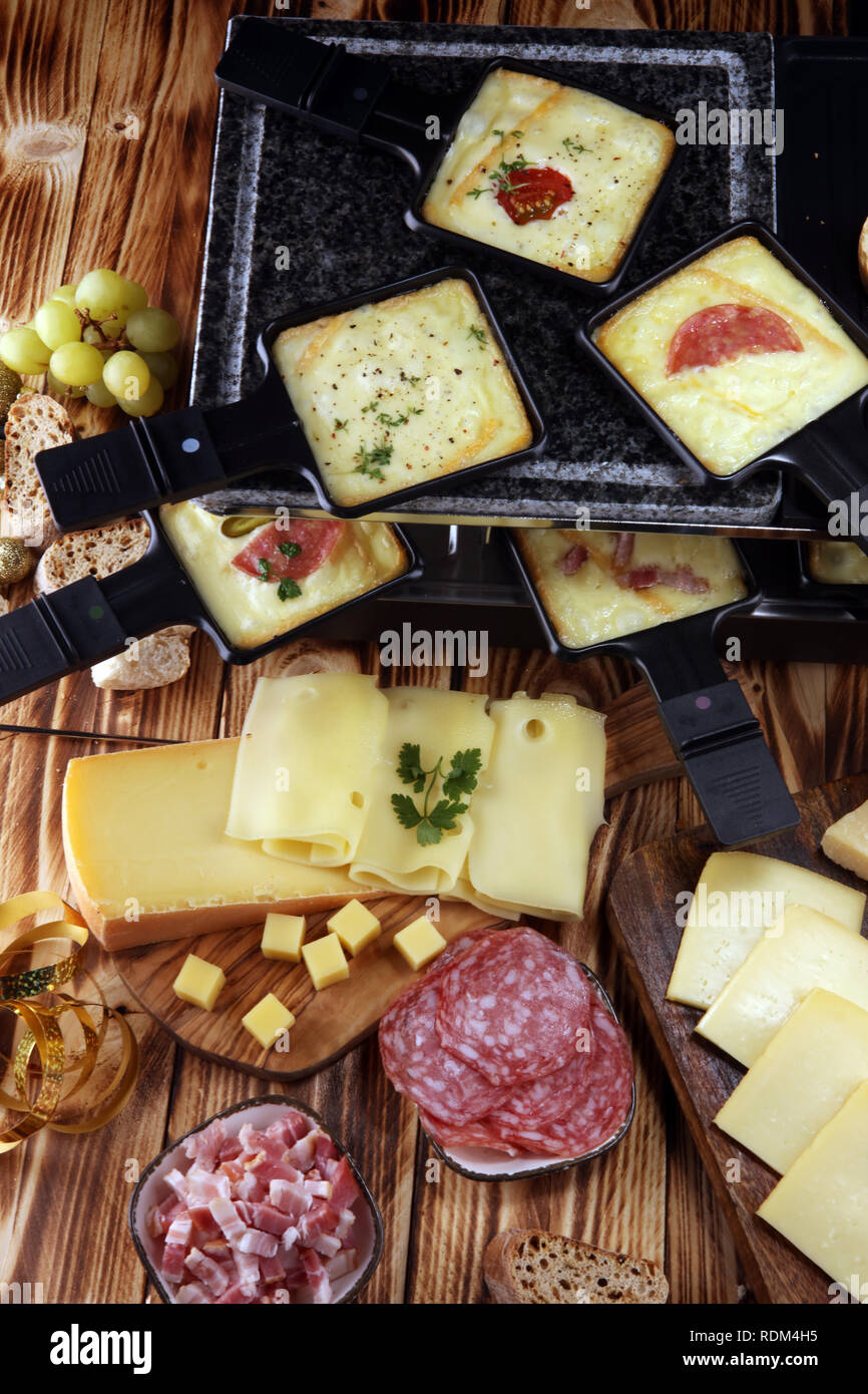 Délicieux fromage à raclette fondue suisse traditionnel servi dans des poêlons au salami Banque D'Images Délicieux fromage à raclette fondue suisse traditionnel servi dans des poêlons au salami Banque D'Images