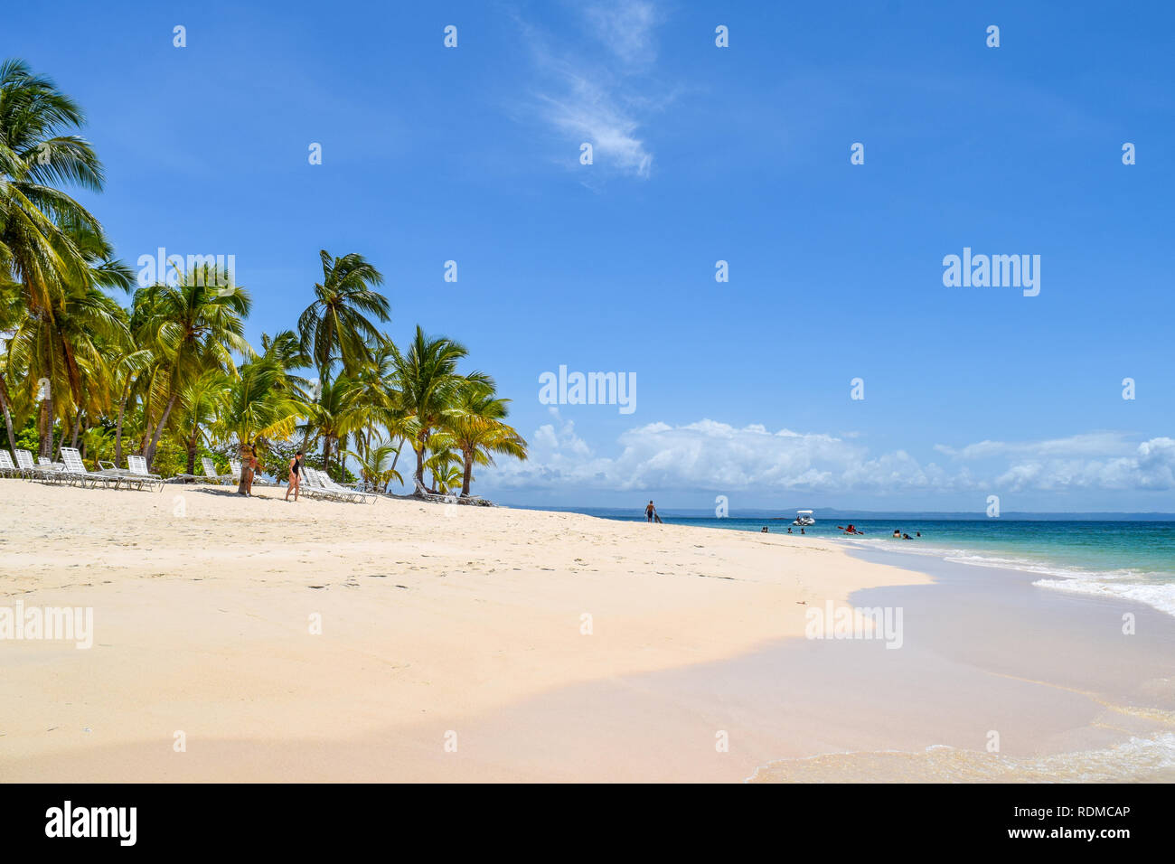 Île tropicale dans la mer des caraïbes avec palmiers, sable blanc, mer turquoise et bleu ciel, certains touristes se détendre dans l'océan et sur la plage Banque D'Images