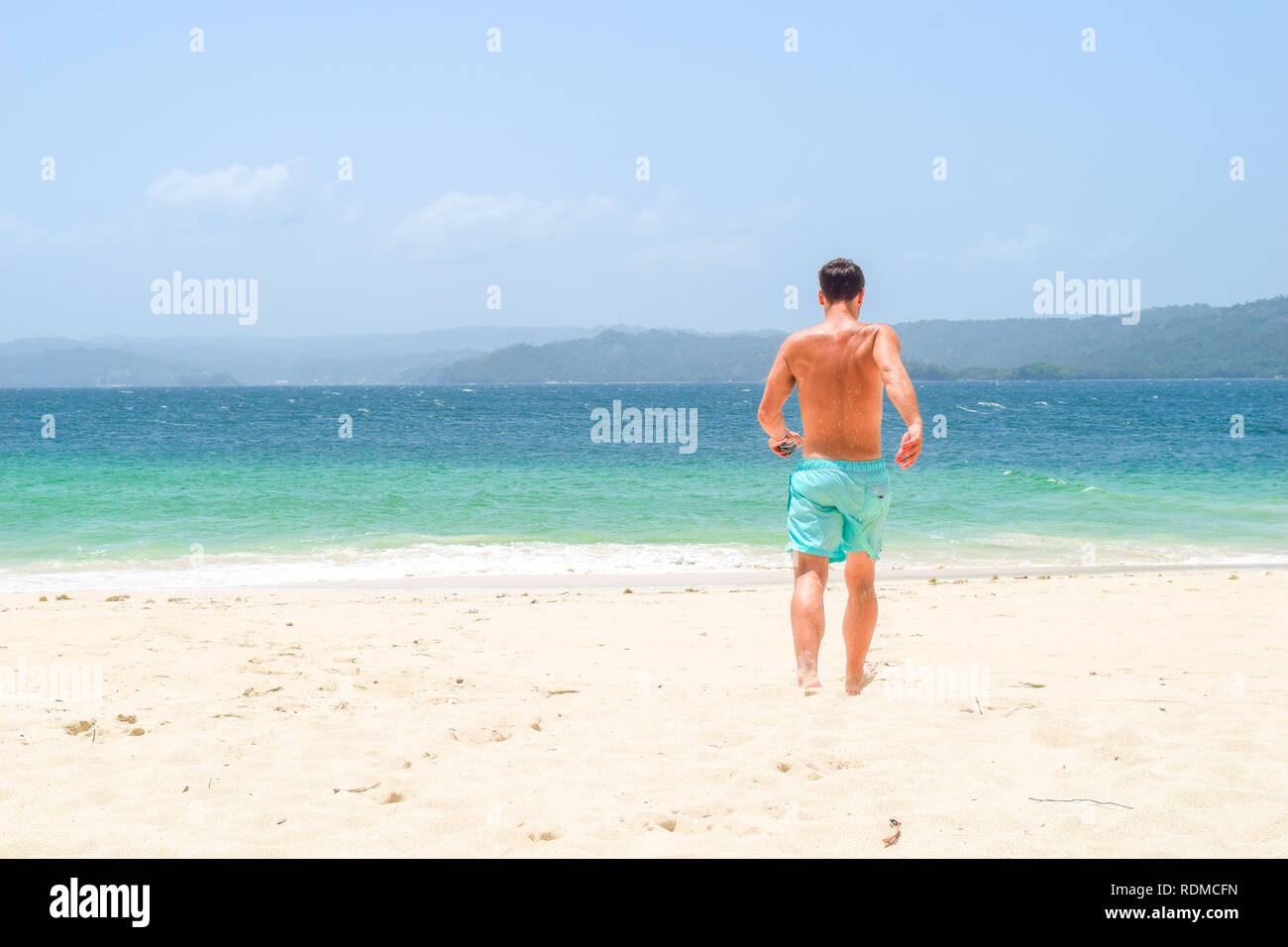 Homme qui courait pieds nus sur la plage dans l'océan turquoise sur une île, la mer des Caraïbes Banque D'Images