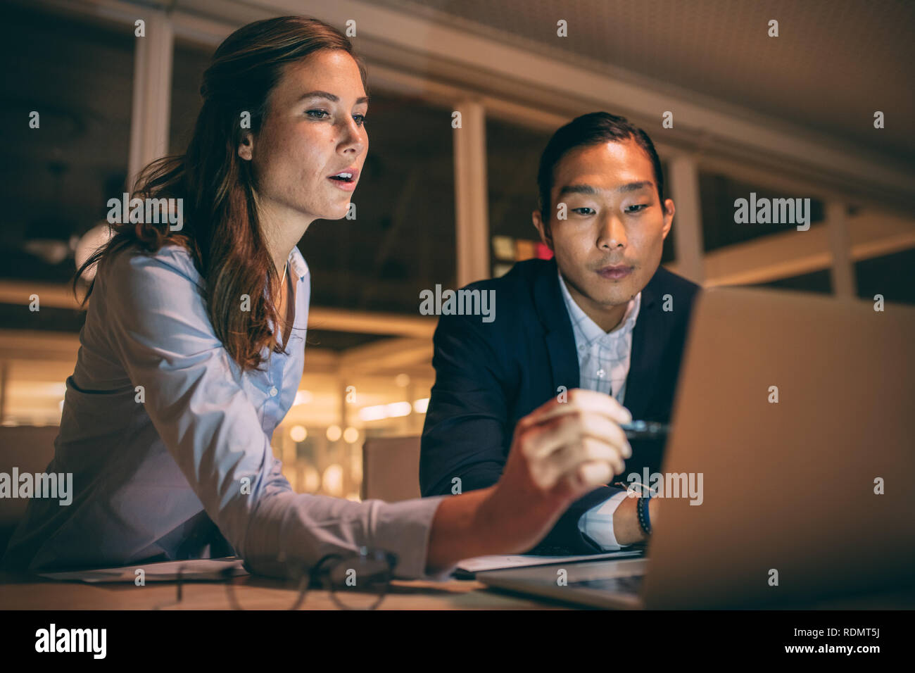 femme d'affaires pointant à l'écran d'ordinateur portable expliquant le travail au partenaire d'affaires. collègues travaillant ensemble assis tard au bureau. Banque D'Images
