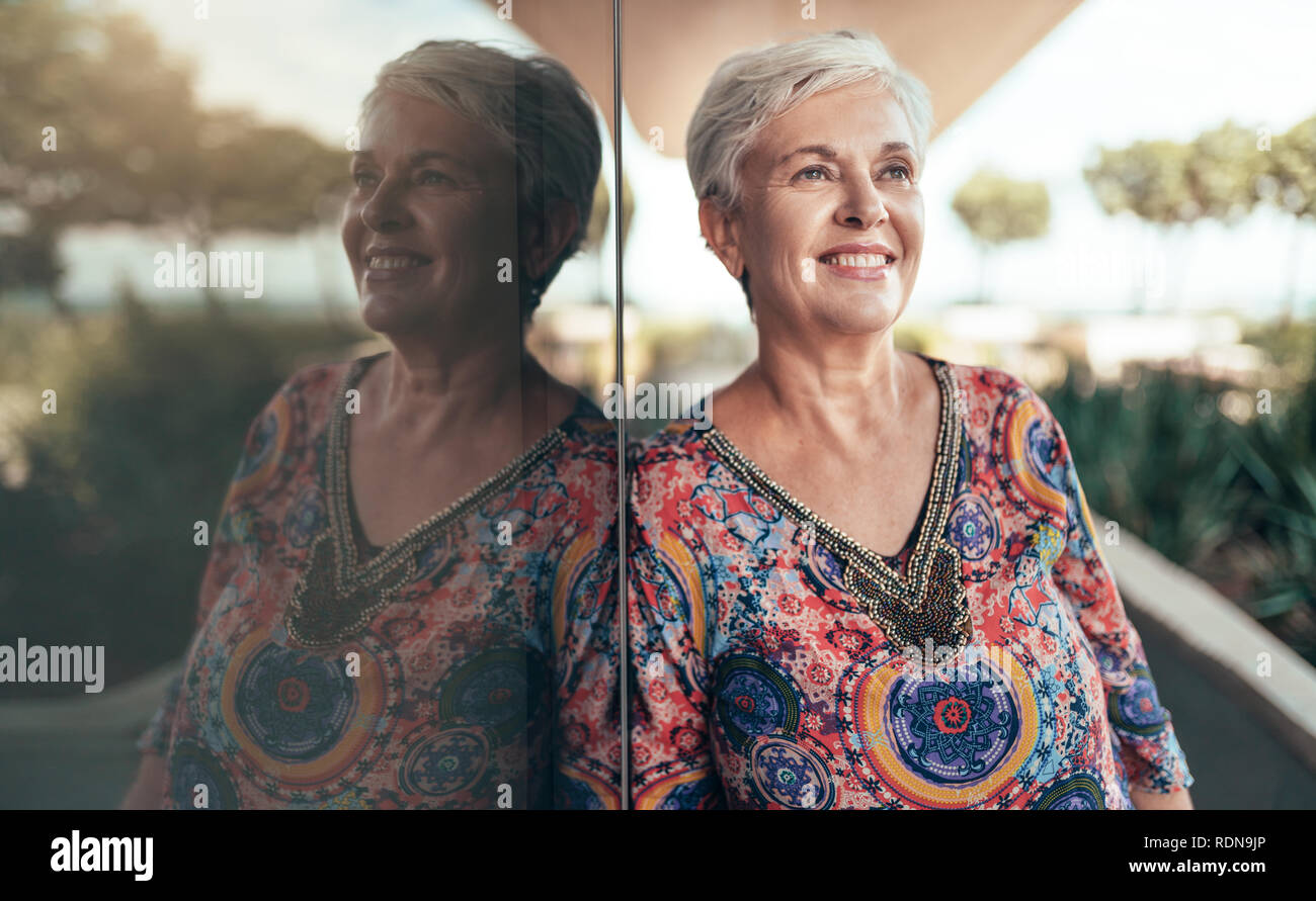 Portrait d'une belle femme d'âge moyen aux cheveux gris regardant dans la distance avec son reflet Banque D'Images