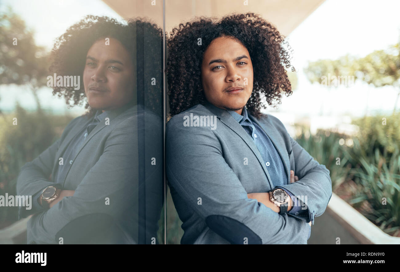 Young mixed race guy avec curly afro à la caméra dans les bras croisés Banque D'Images