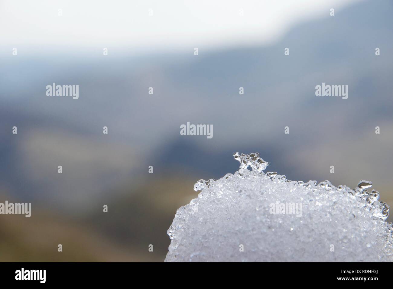 Sharp shot de blanc et de dégager la neige et les cristaux de glace sur une boule de neige. Dans les montagnes de Lake District, Cumbria (Royaume-Uni) en arrière-plan flou. Banque D'Images