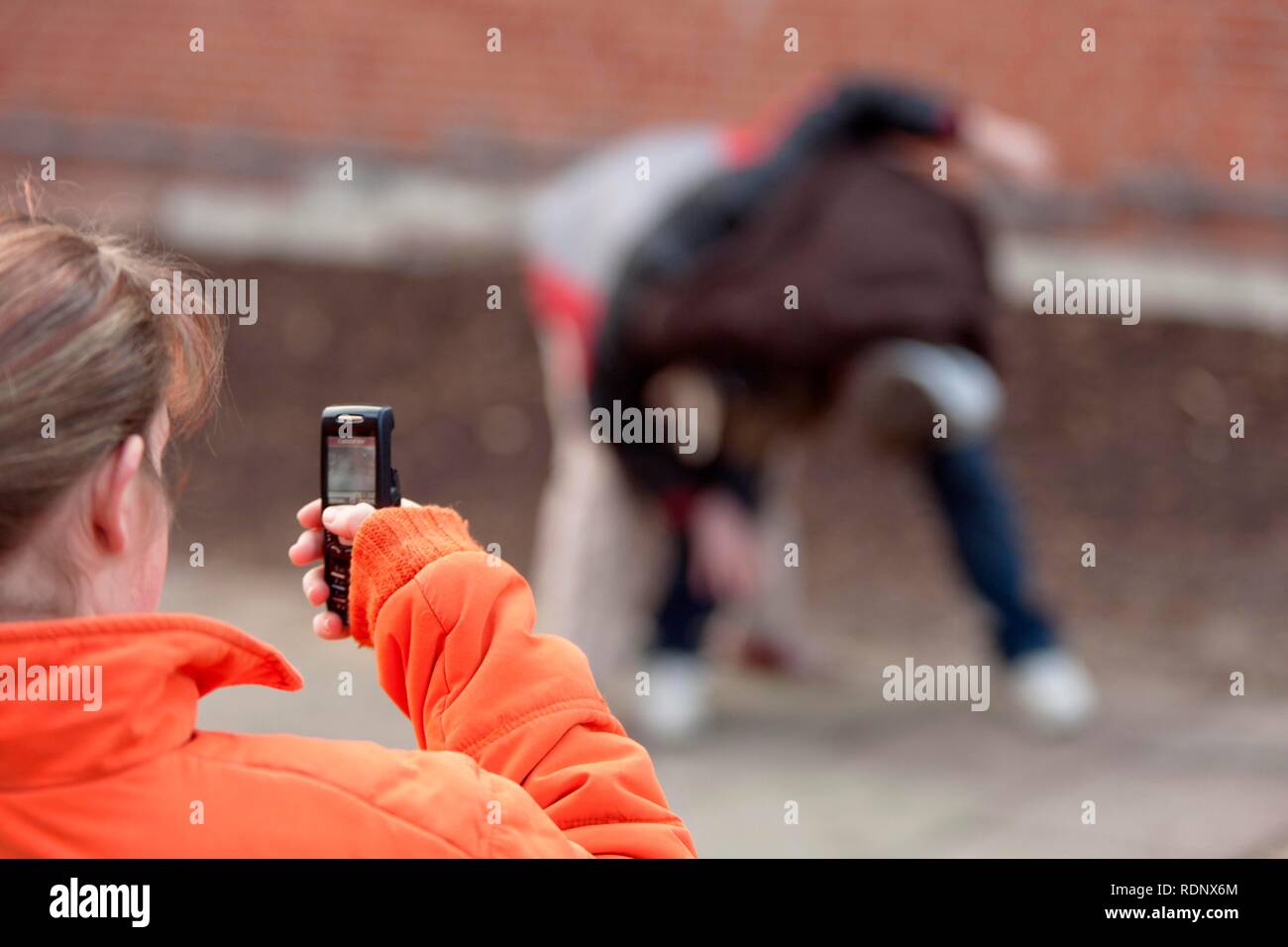 Deux garçons lutte et filmés par une fille avec son téléphone mobile, reenactment Banque D'Images