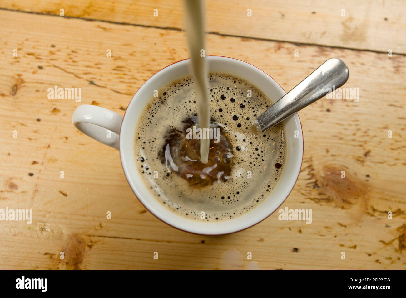 Vue aérienne de lait est versé dans une tasse de café Banque D'Images