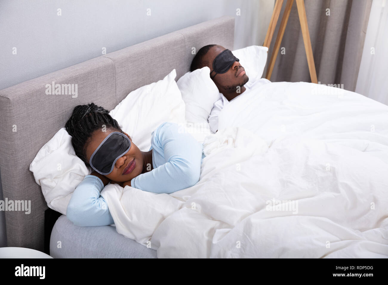 Jeune couple dormir sur lit à l'aide de masque pour les yeux dans la chambre Banque D'Images