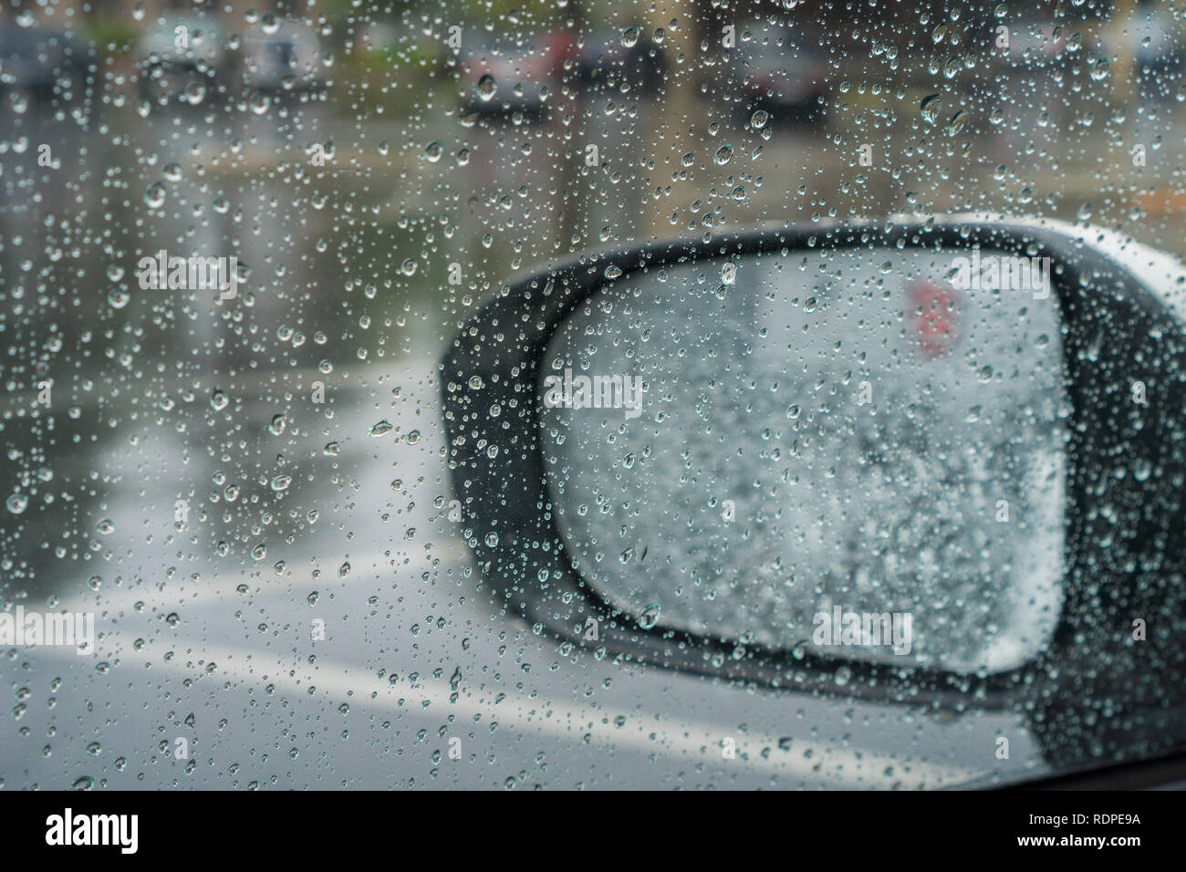 Gouttes de pluie sur la fenêtre et sur le miroir de l'aile ; la chaussée mouillée dans l'arrière-plan ; profondeur de champ Banque D'Images