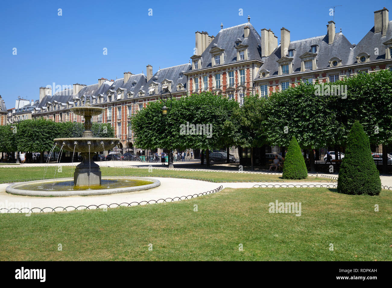 Place des Vosges, anciens bâtiments et jardin à Paris dans un beau jour d'été, ciel bleu clair Banque D'Images