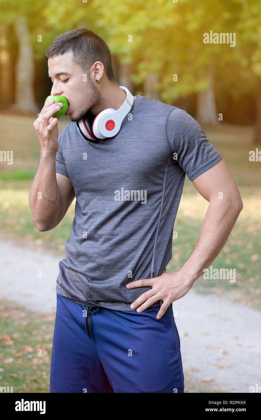 Jeune homme latin Runner eating apple vertical tournant sports outdoor fitness jogging formation Banque D'Images