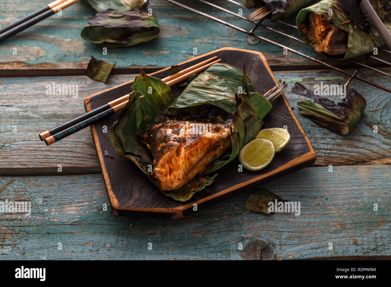 Le Sambal stingray dans une feuille sur une planche en bois, une cuisine malaisienne, copy space Banque D'Images