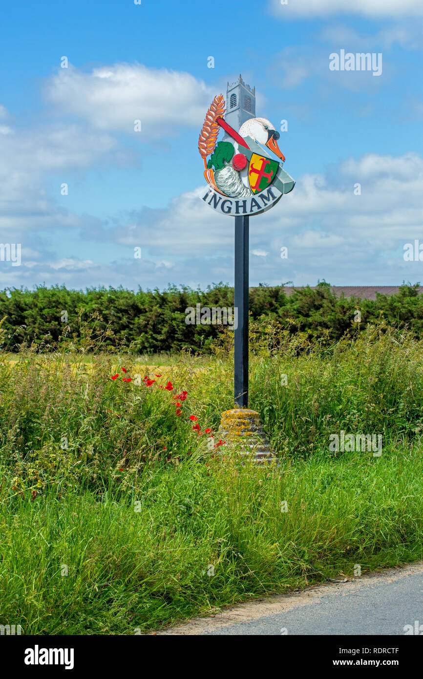 Ingham Panneau du village. Bord de la route. ​Norfolk. De l'East Anglia, Angleterre, Royaume-Uni. ​Midst coquelicots et l'ensemencement de graminées. Historique illustrant l'occupation actuelle de l'agriculture, et des sujets sportifs d'intérêt local. Banque D'Images