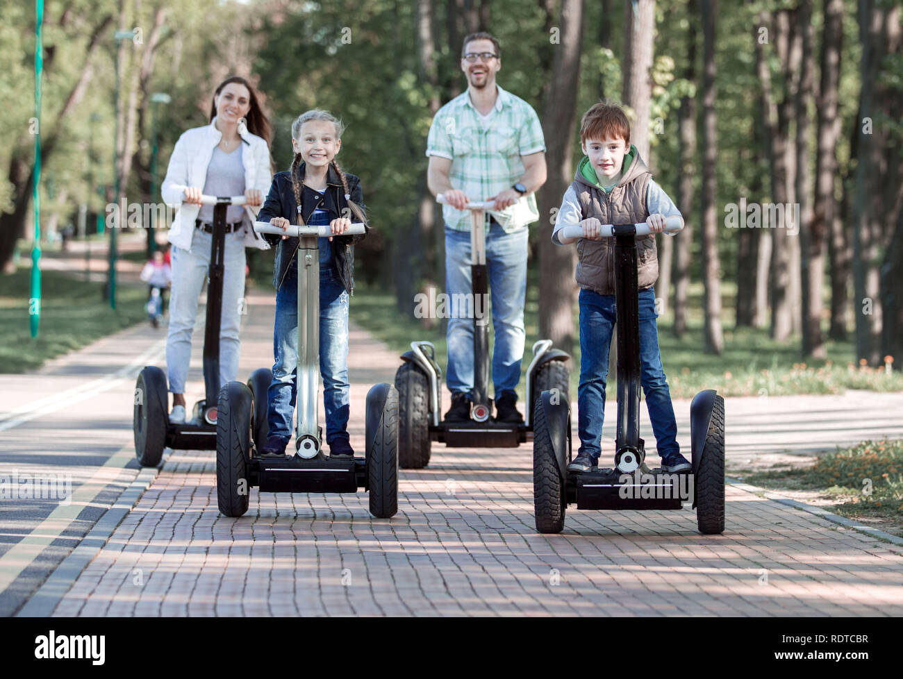 Happy Family riding scooter électrique dans le parc . Le concept de  famille. Nous avons rendez-vous ensemble Photo Stock - Alamy