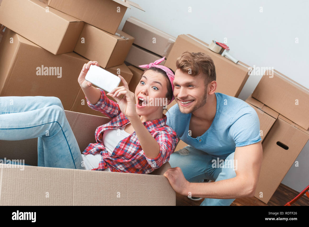 Jeune couple déménagement au nouveau lieu femme en fort de prendre des photos avec des selfies homme heureux Banque D'Images
