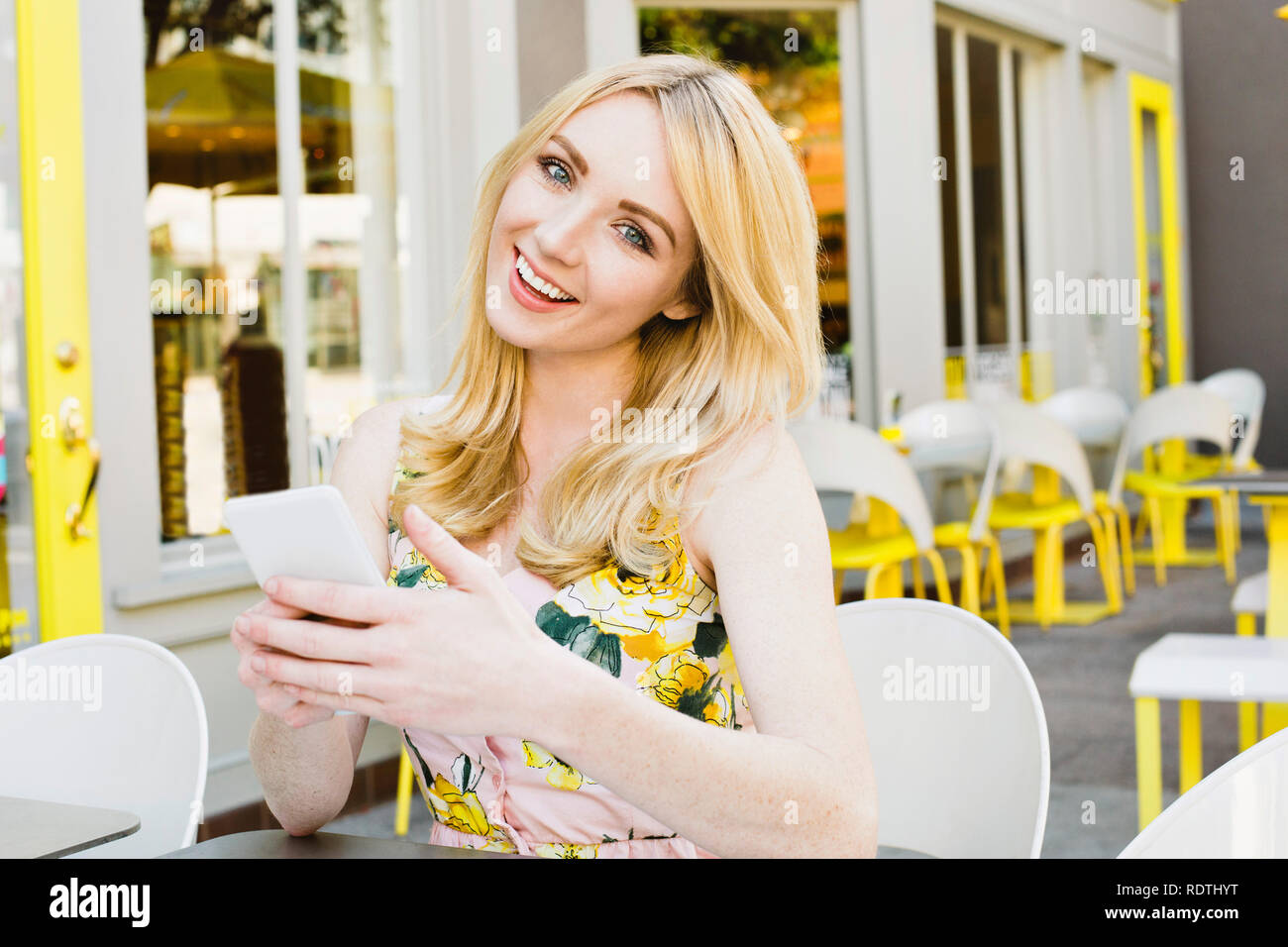 Jolie jeune femme blonde est titulaire d'un téléphone cellulaire et sourit est heureux et All American Girl Banque D'Images