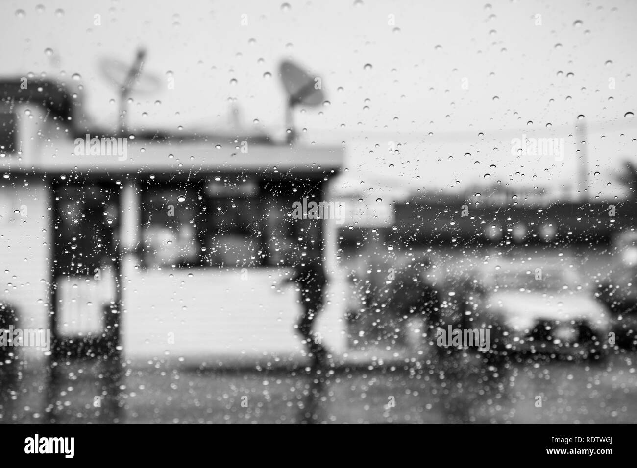 Gouttes de pluie sur le pare-brise ; personne qui marche à l'extérieur par temps de pluie à l'arrière-plan ; Californie ; noir et blanc Banque D'Images