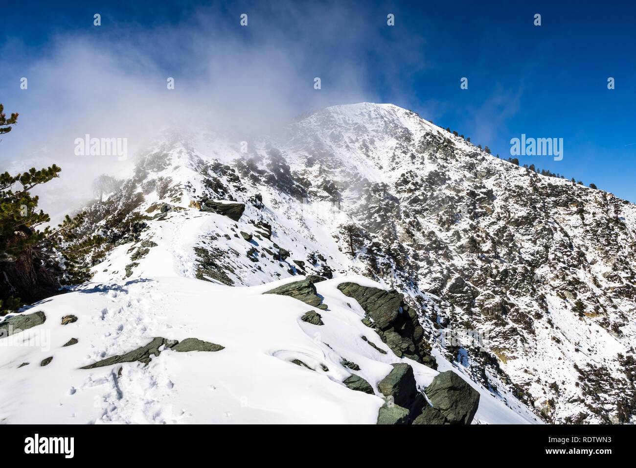 La crête rocheuse sur le sentier vers le sommet du Mont San Antonio (Mt Baldy) sur la neige mais journée ensoleillée, avec du brouillard passant de la Valley, comté de Los Angeles Banque D'Images