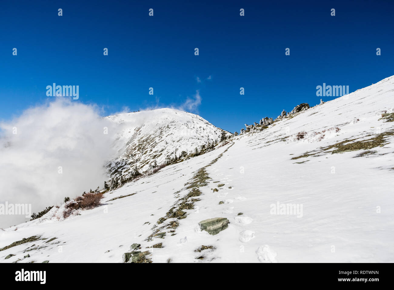 La randonnée au sommet du Mont San Antonio (Mt Baldy) sur une journée de printemps ensoleillée, avec frozen couvrant la piste, le comté de Los Angeles, Californie du sud Banque D'Images