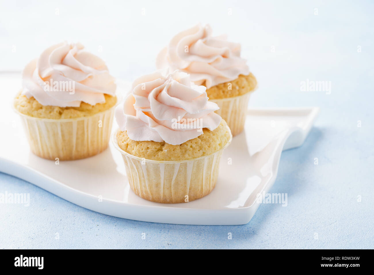 Cupcakes Vanille rose sur fond bleu clair. Des couleurs pastel. Banque D'Images