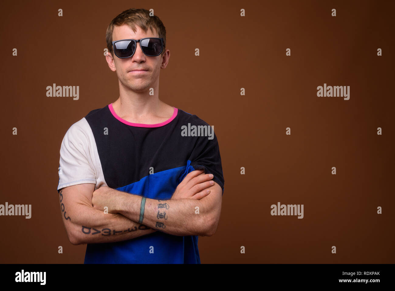Homme portant une chemise bleue et lunettes contre fond brun Banque D'Images