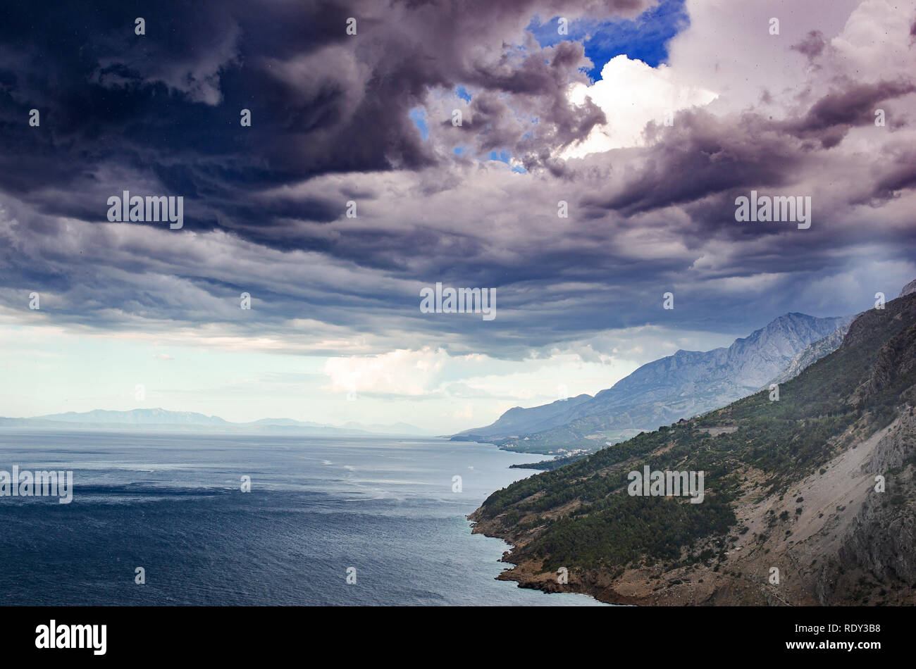 Paysage côtier. Seashore avec montagnes rocheuses sur fond de ciel pluvieux spectaculaire. Banque D'Images
