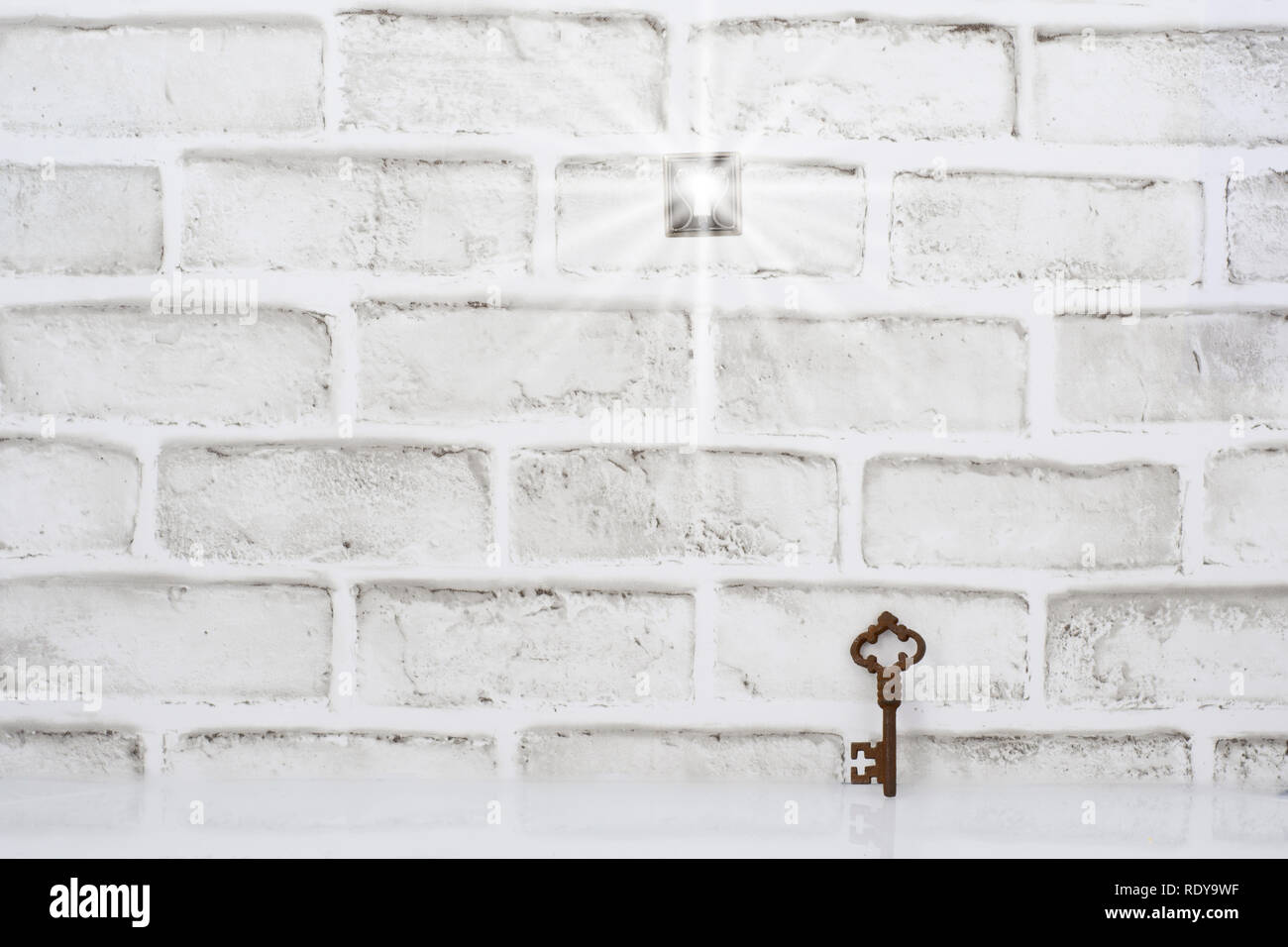 Un trou de serrure dans un mur de brique avec une lumière qui brillait à travers. La clé est ici, mais il n'y a pas de porte et il n'est pas clair si passer par est poss Banque D'Images