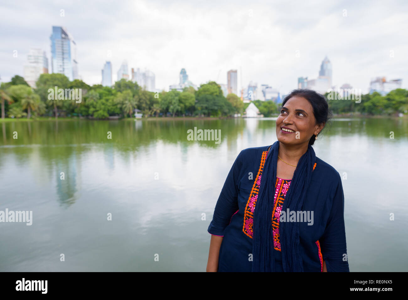Belle mature Indian woman smiling and thinking in park Banque D'Images