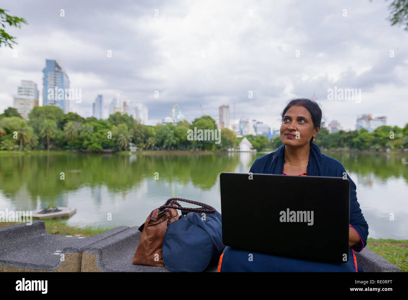 Portrait of mature femme indienne à park en utilisant un ordinateur portable Banque D'Images