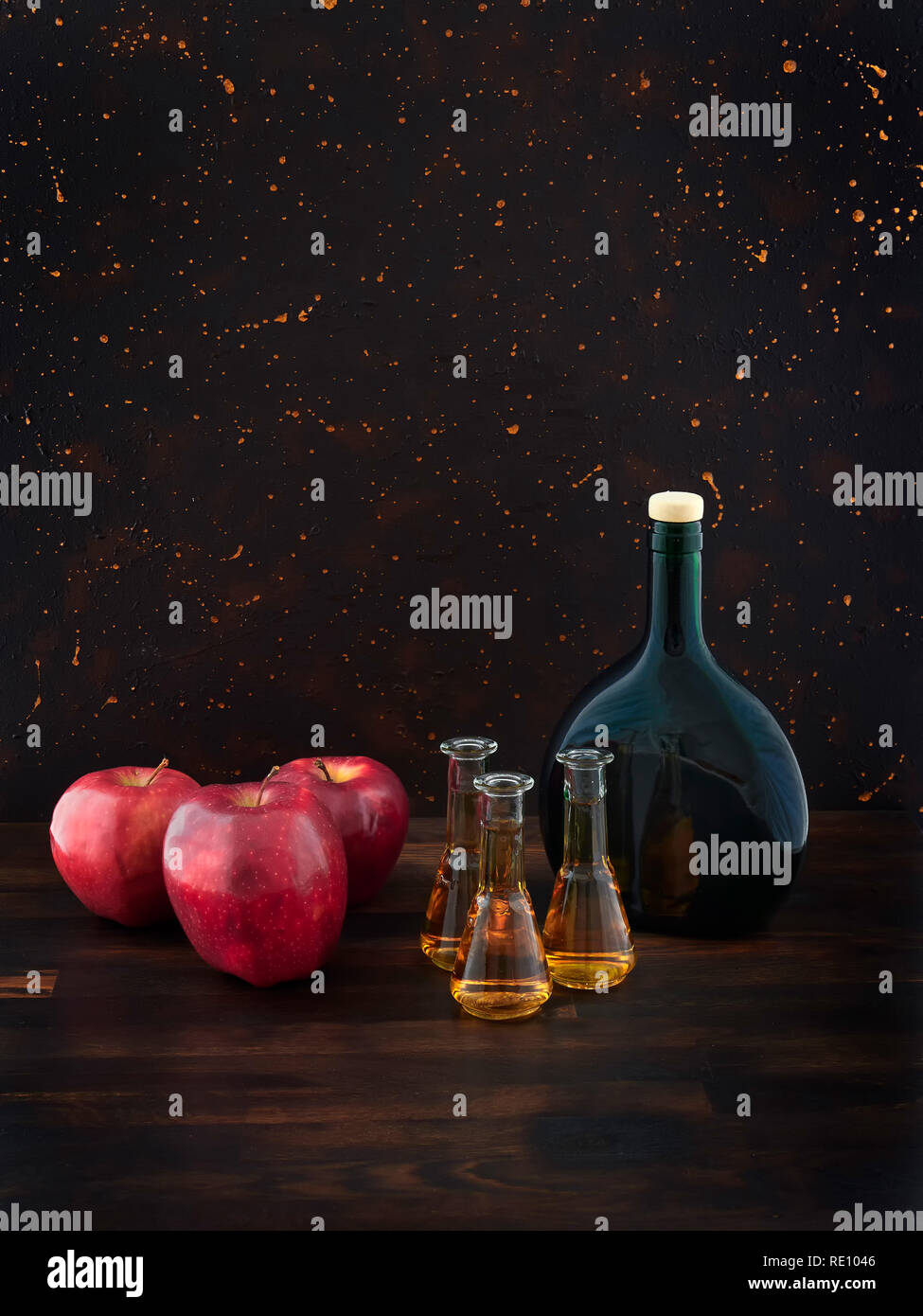 De pomme ou de Calvados, pommes rouges et un vert bouteille, sur une planche en bois foncé, avec un fond brun foncé Banque D'Images