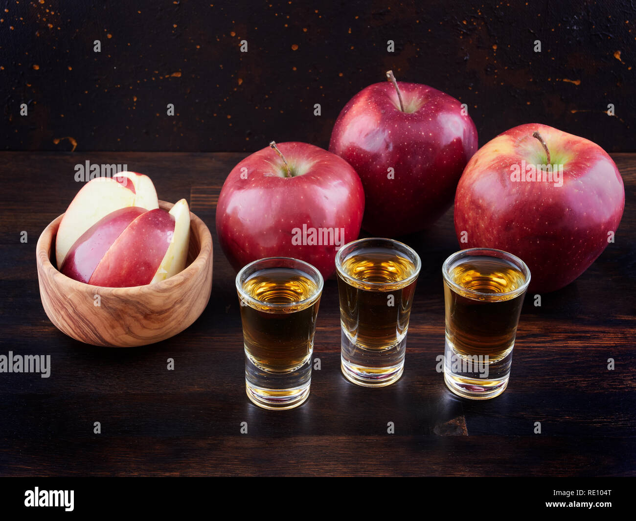 De pomme ou le Calvados et pommes rouges, sur une planche en bois foncé, avec un fond brun foncé Banque D'Images