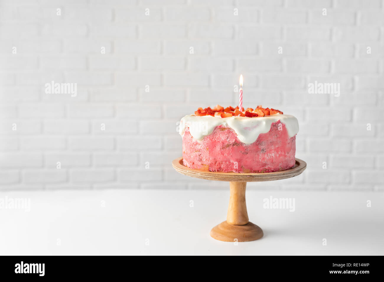 Gâteau aux fraises avec une bougie allumée sur blanc Banque D'Images