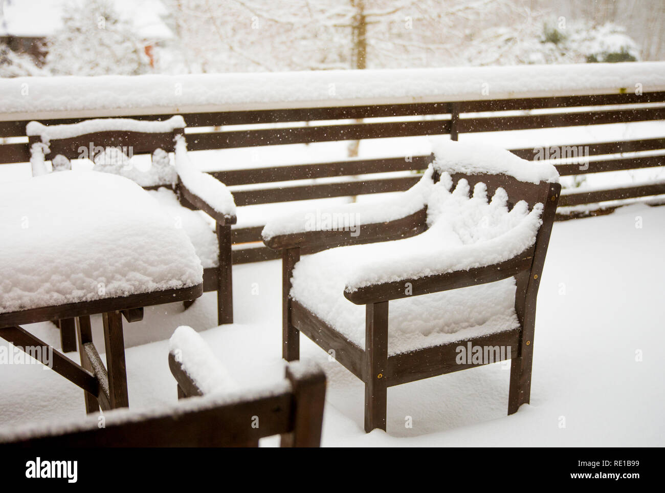 La neige propre frais couvrant en bois teinté brun acajou table et chaises de jardin sur balcon accueil. Meubles de jardin entretien après l'hiver froid Banque D'Images