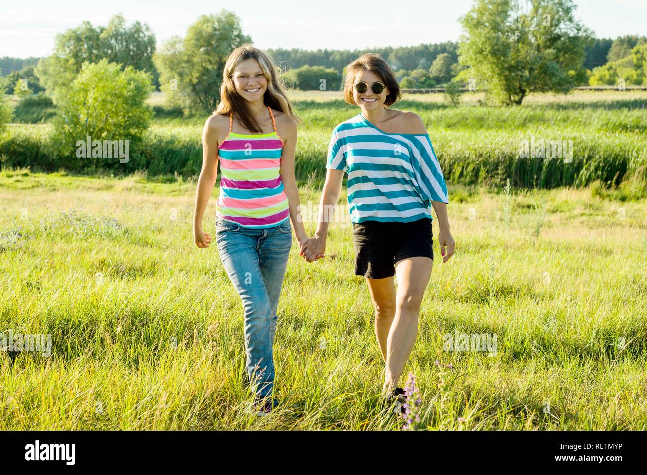 Mère et fille de l'adolescence se tenant la main. Photo sur la nature en journée ensoleillée. Banque D'Images