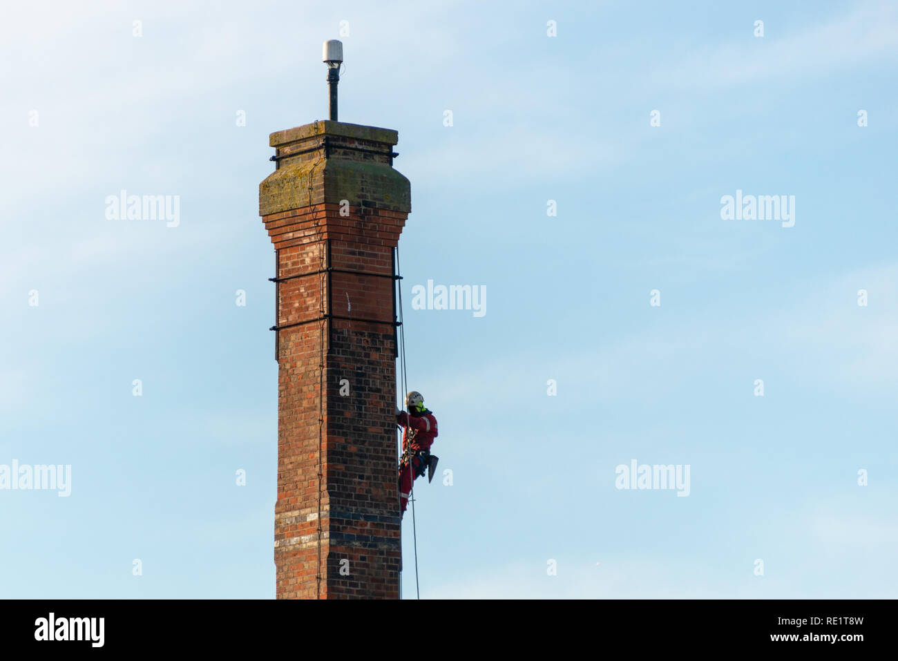 L'homme faisant un travail dangereux steeplejack descendre la haute tour de briques à l'aide de cordes Banque D'Images