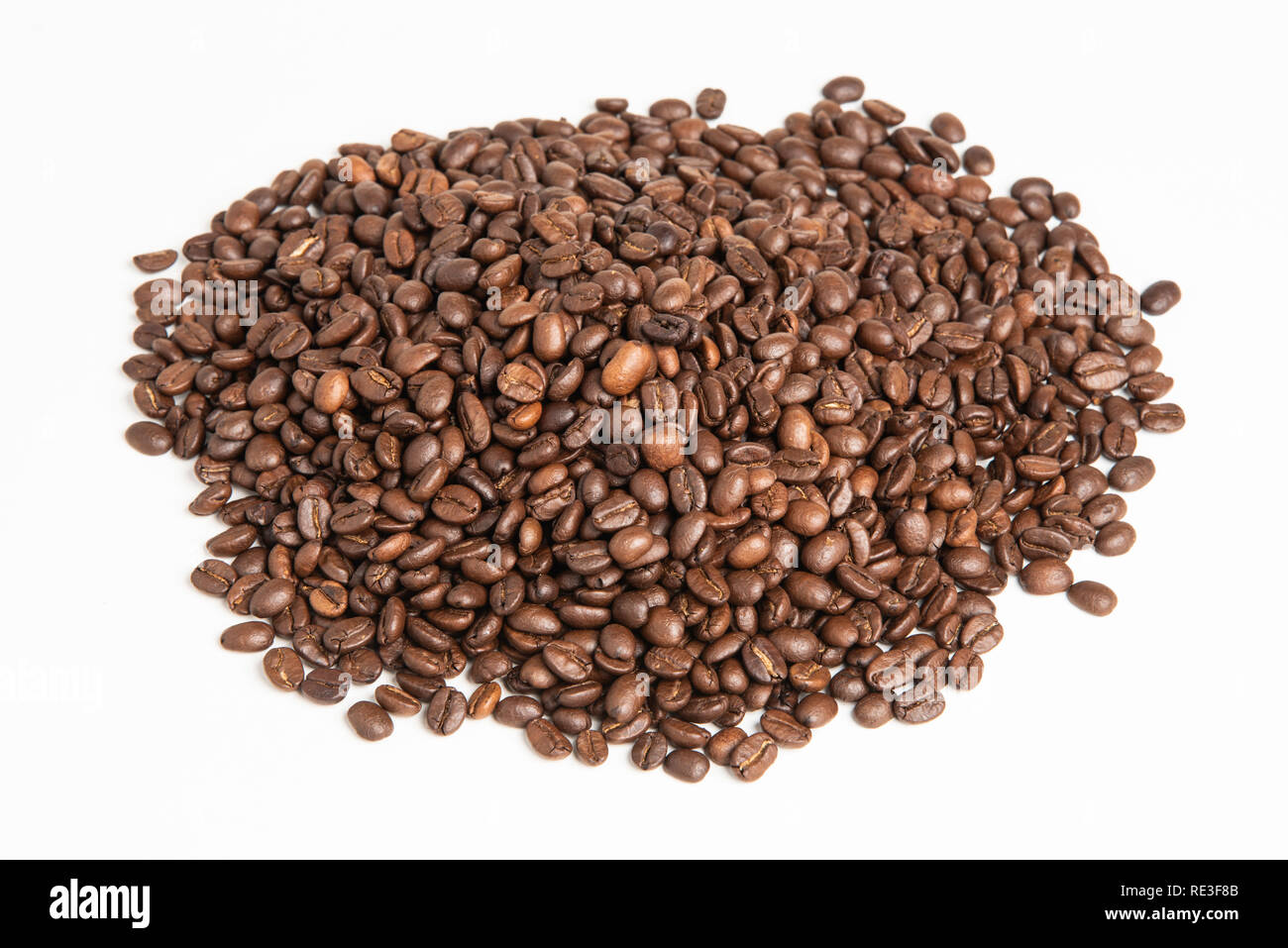 Un grand monticule de rôti foncé et séché de café arabica situé sur un arrière-plan uni, blanc. Banque D'Images