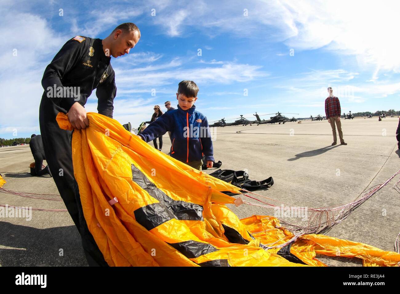 Membre de l'armée américaine Golden Knights pliages son parachute avec le peu d'aide d'un jeune spectateur après le saut dans l'organisation de la famille day organisé par la 82e Brigade d'aviation de combat, Fort Bragg, N.C., 22 novembre 2016. Banque D'Images
