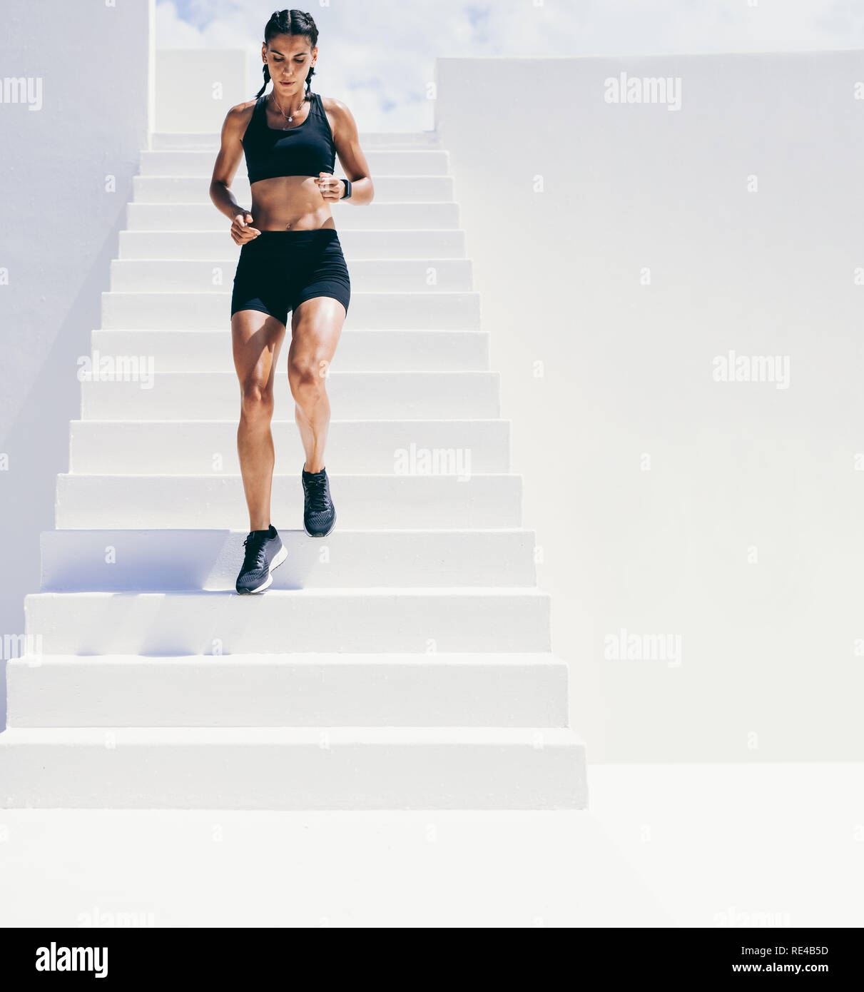 Athlète féminin fonctionnant en bas de l'escalier d'un immeuble. Femme en faisant porter fitness workout fonctionnant en bas. Banque D'Images