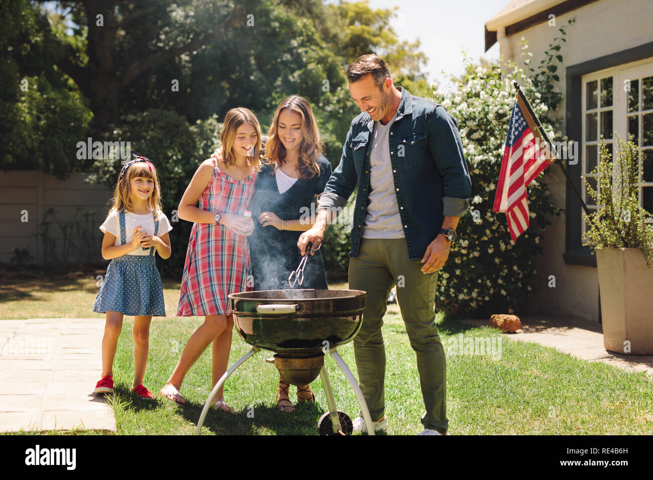De la cuisson des aliments ensemble dans leur arrière-cour. Faire de l'homme permanent barbecue dans leur cour avec femme et enfants. Banque D'Images