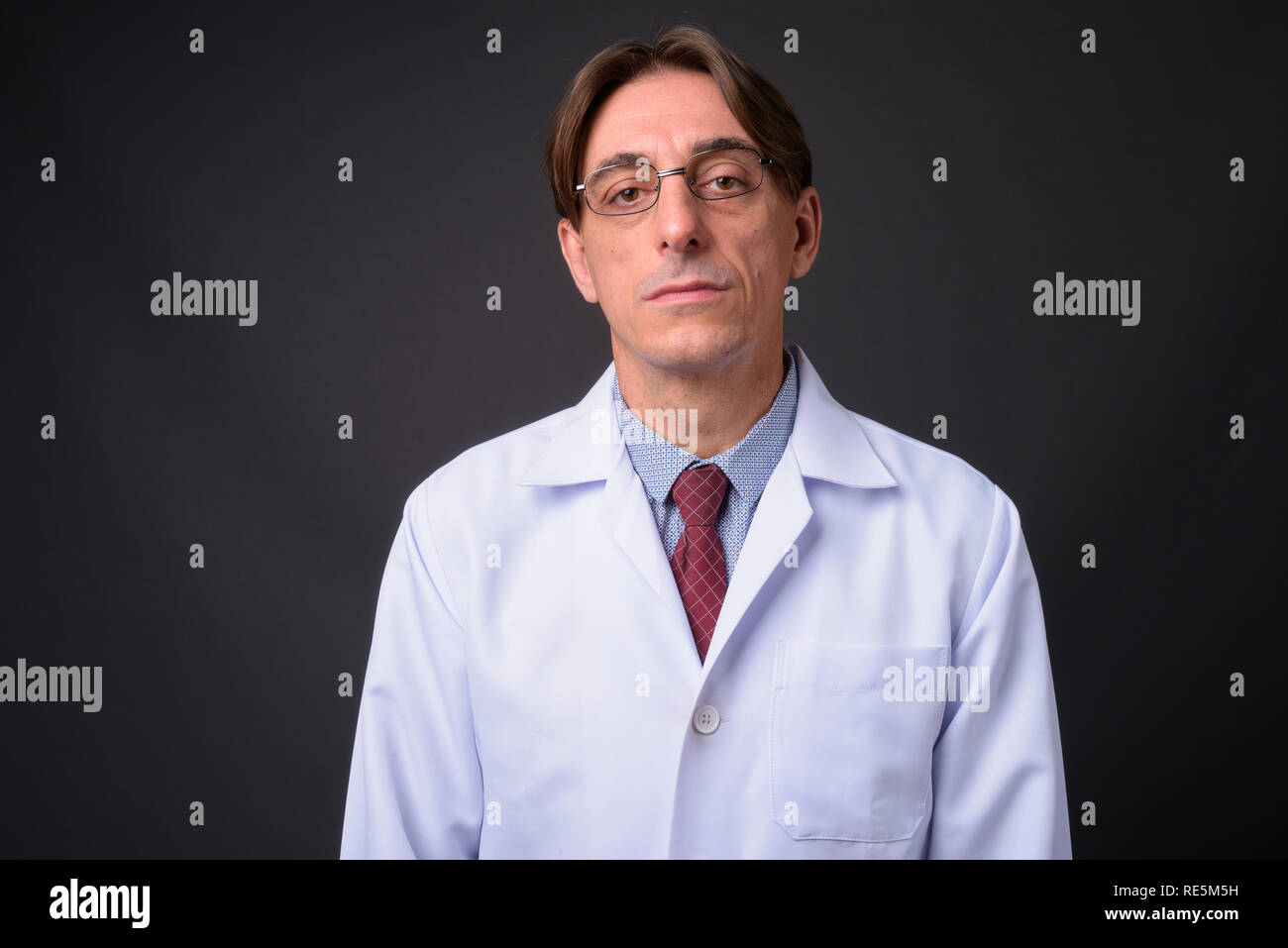 Homme mature beau médecin italien contre l'arrière-plan gris Banque D'Images