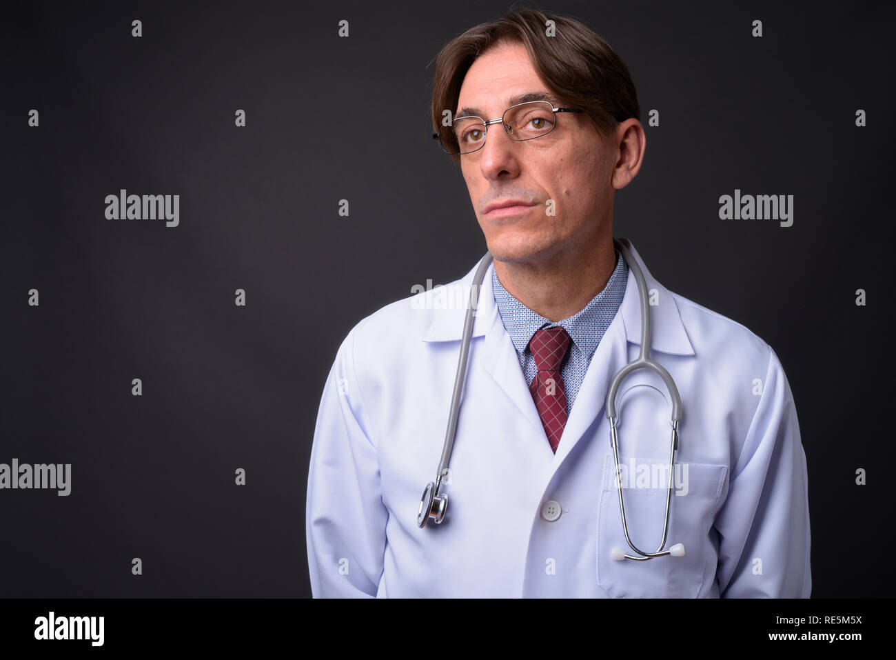 Homme mature beau médecin italien pensée contre fond gris Banque D'Images