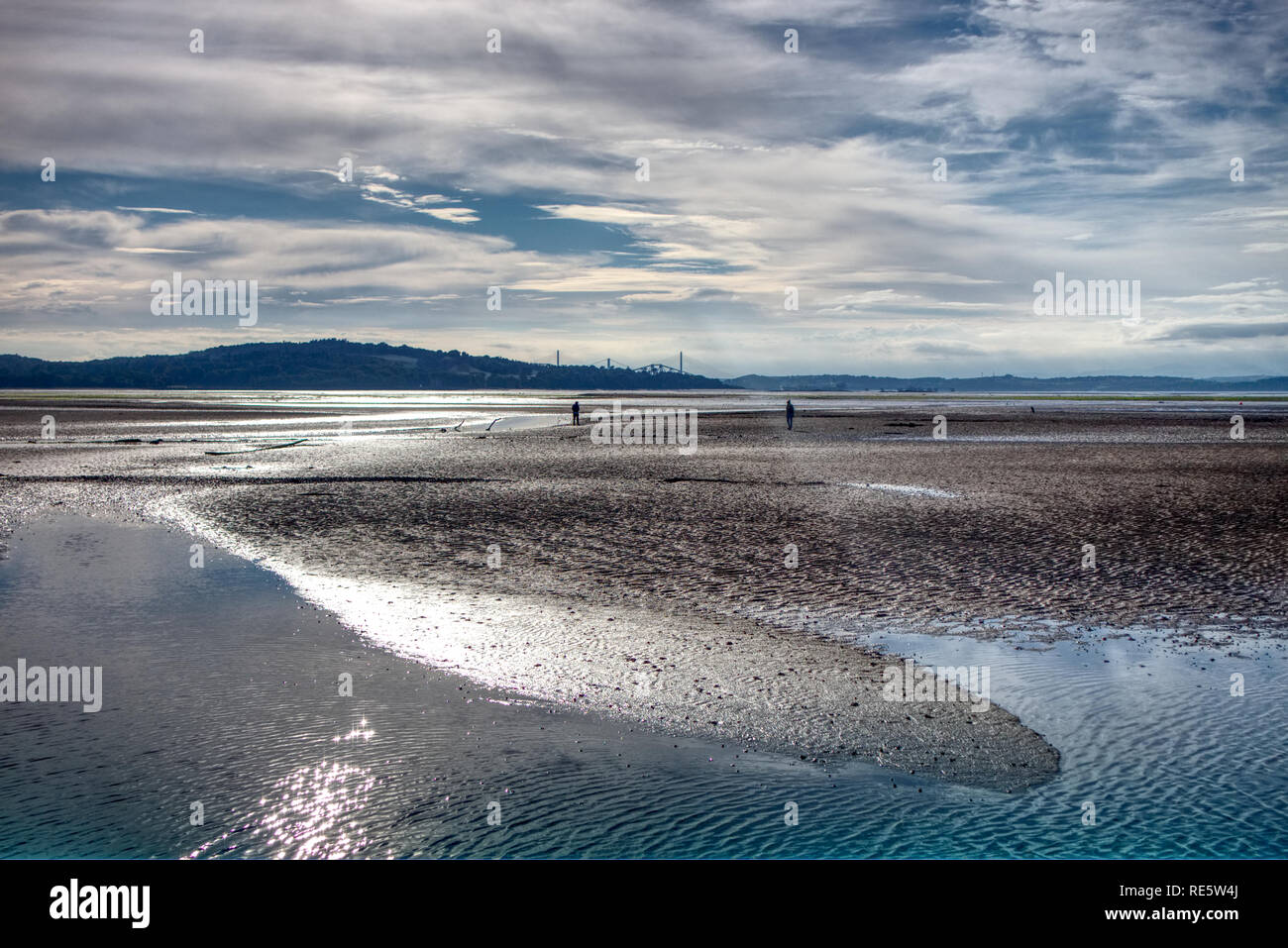 Une photo de deux personnes se demander sur la plage entourant l'île de Cramond dans le Firth of Forth près d'Edimbourg, Ecosse, à marée basse Banque D'Images