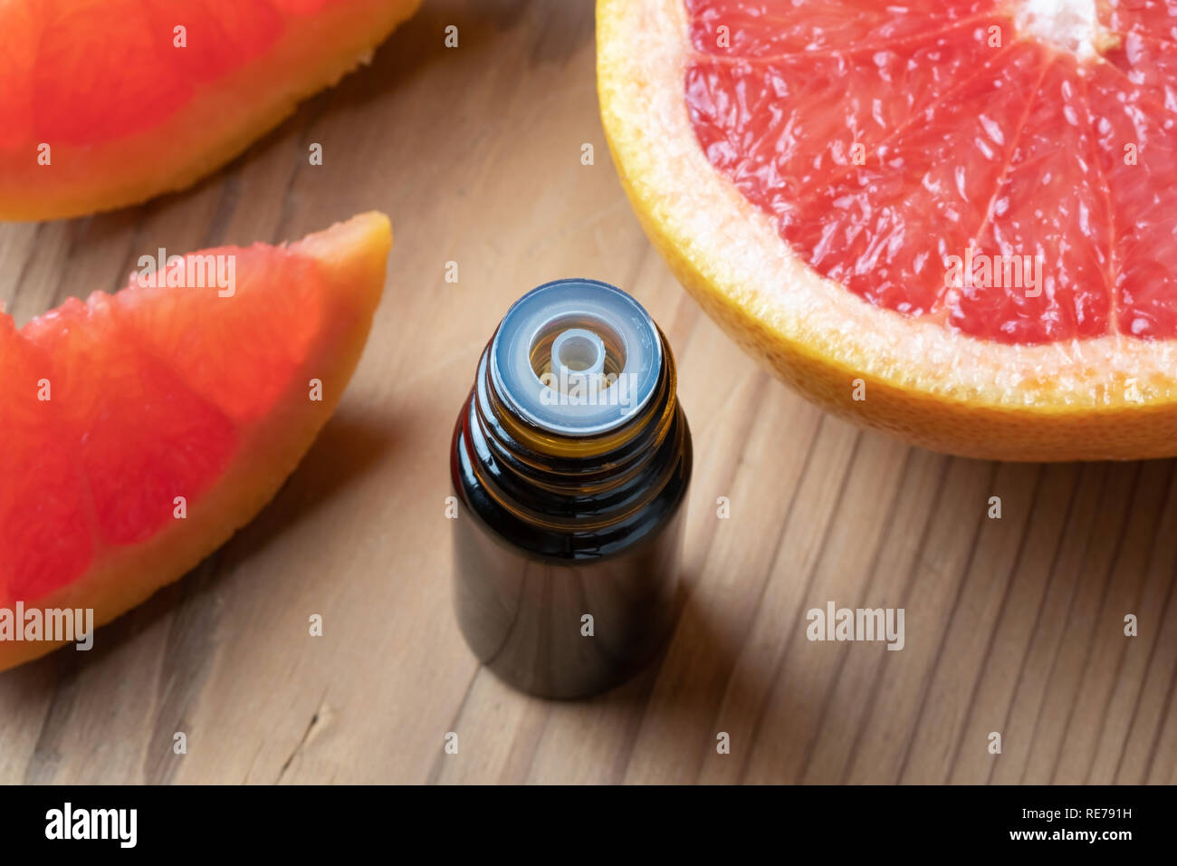 Une bouteille d'huile essentielle d'agrumes avec des pamplemousses frais Banque D'Images