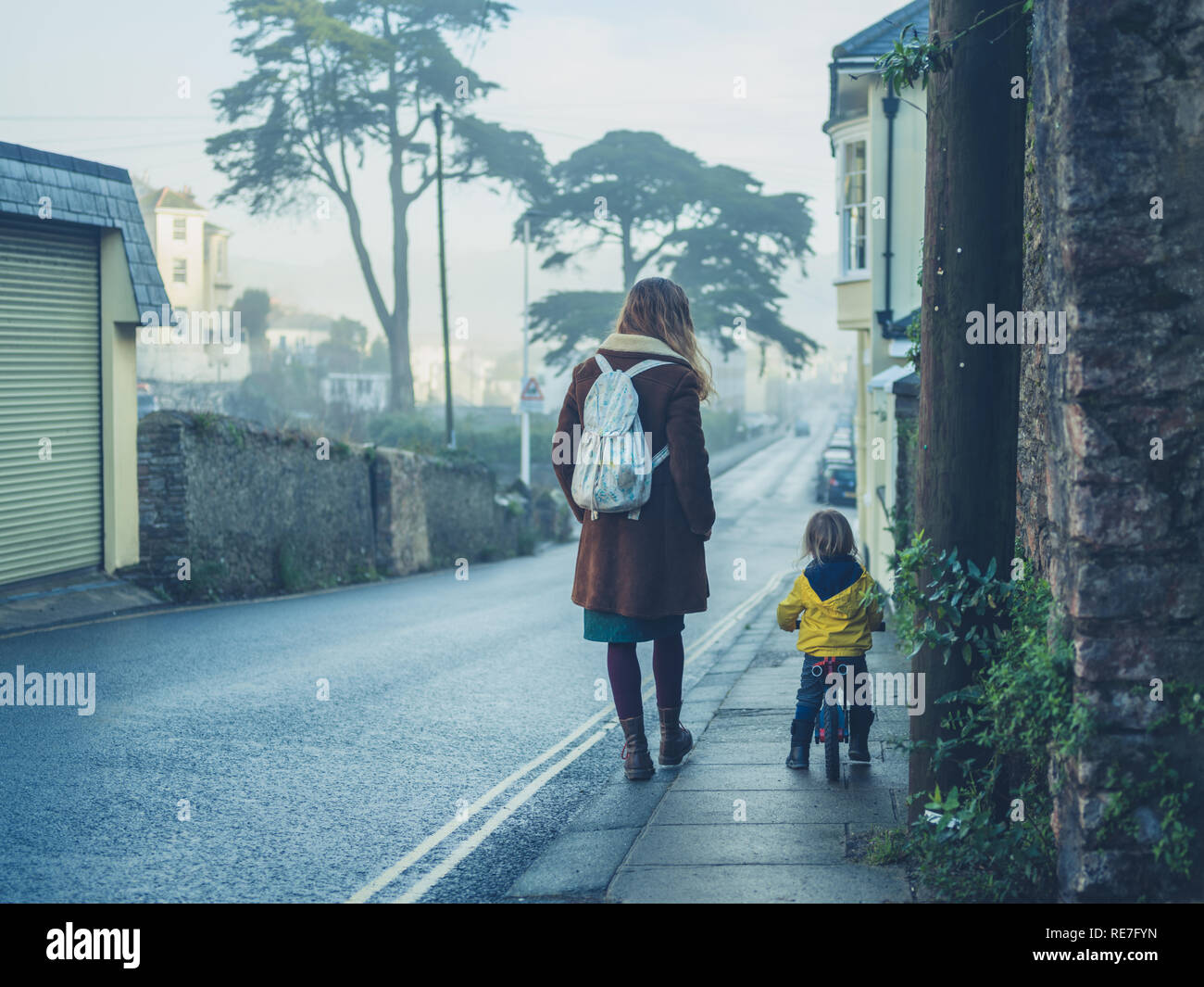 Une mère, c'est marcher dans la rue avec son tout-petit qui est monté sur un vélo équilibre Banque D'Images