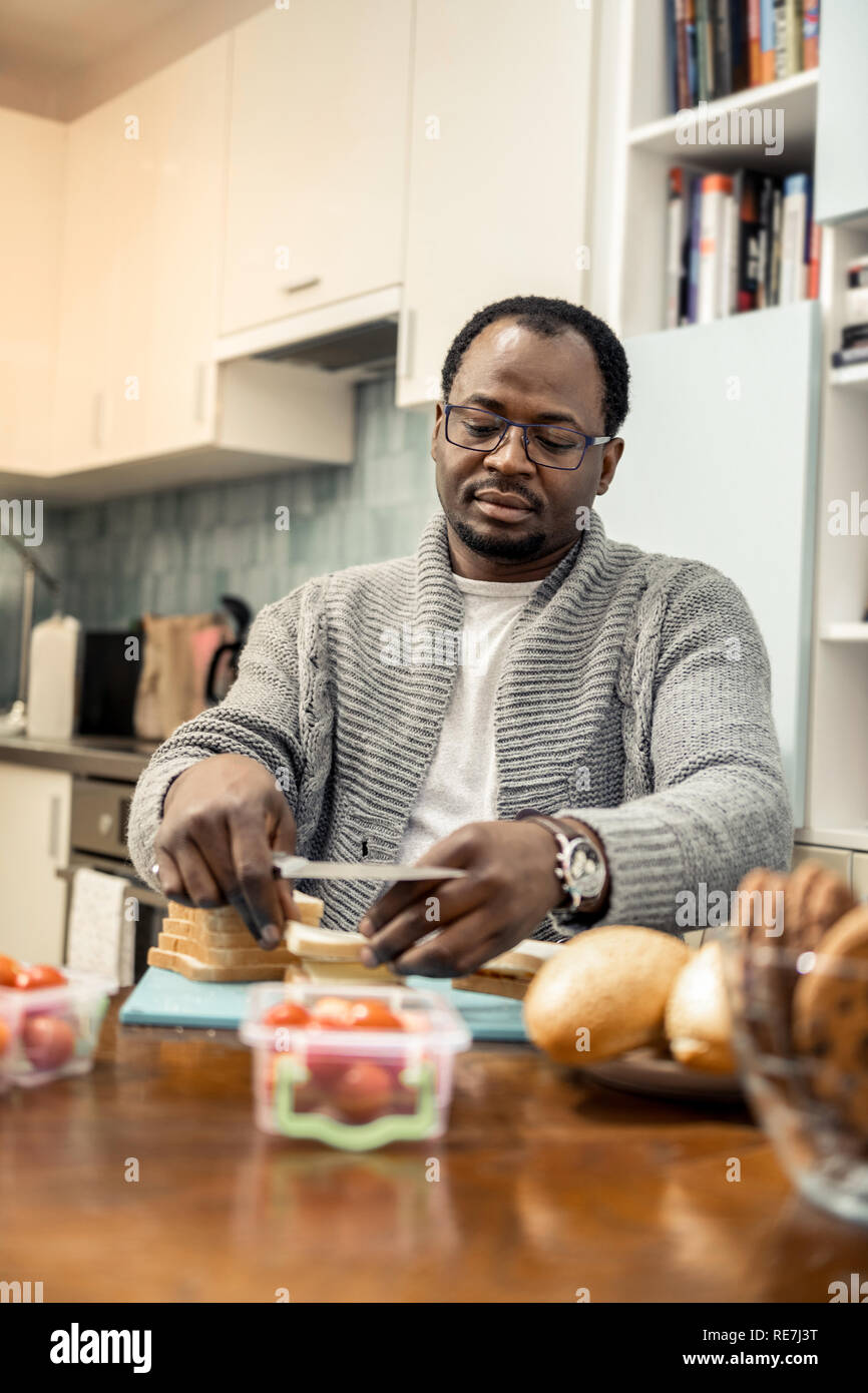 L'homme afro-américain de faire des sandwichs au jambon et légumes Banque D'Images