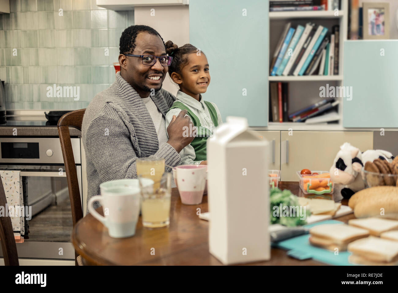 Transmission d'heureux père et fille assis dans la cuisine Banque D'Images
