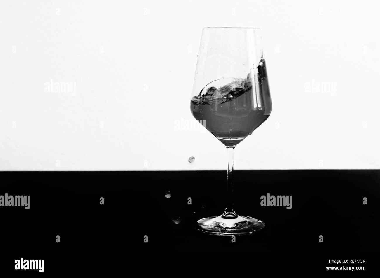 Photo en noir et blanc de vin rouge projection d'un verre Banque D'Images
