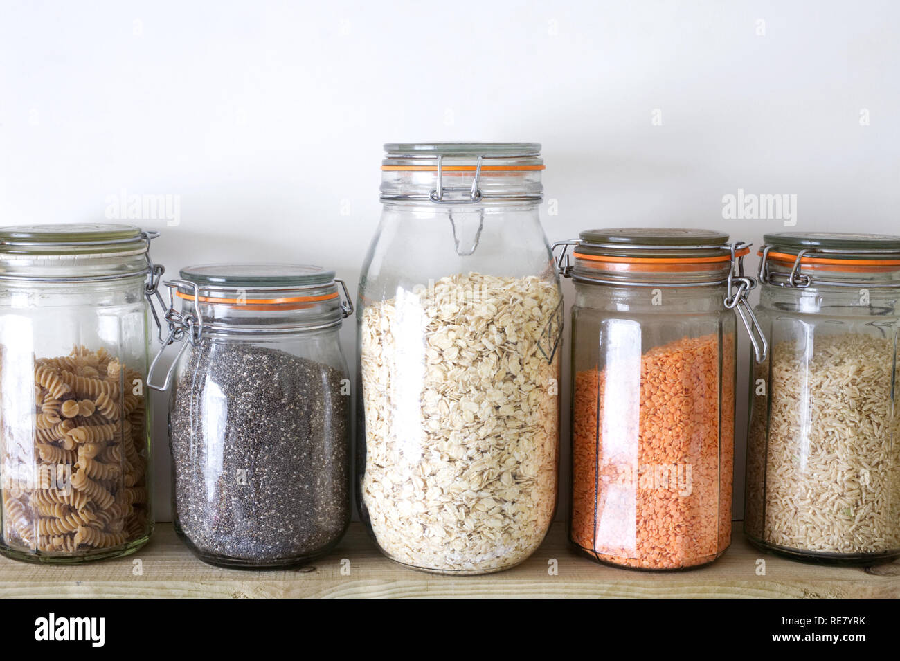 L'avoine, les lentilles, les graines de chia, de riz brun et de la farine complète de pâtes alimentaires dans des bocaux de stockage en verre. Banque D'Images