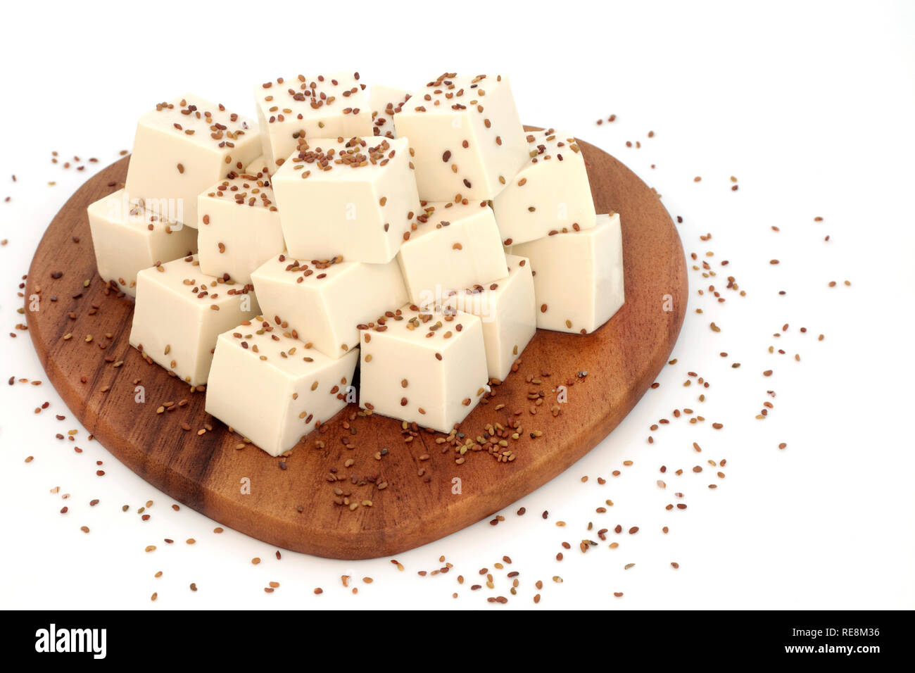 Le Tofu caillé saupoudrés de graines de luzerne sur une planche en bois sur fond blanc. Nourriture santé pour les végétaliens. Riche en protéines et d'oméga 3. Banque D'Images